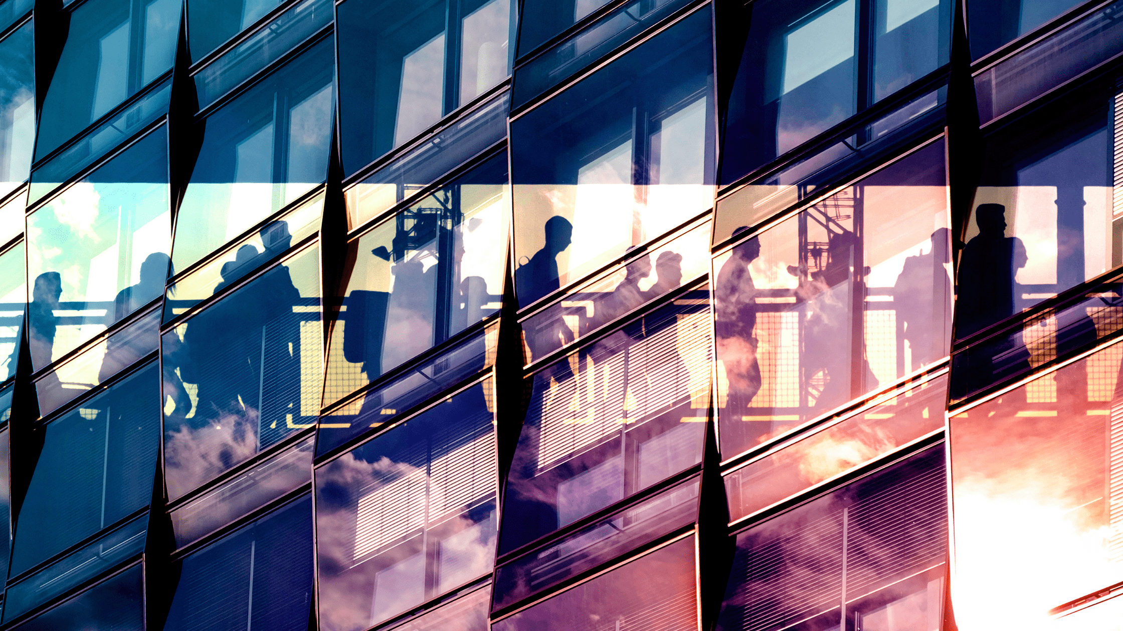 Abstract image of a building facade with people inside walking on a bridge walkway