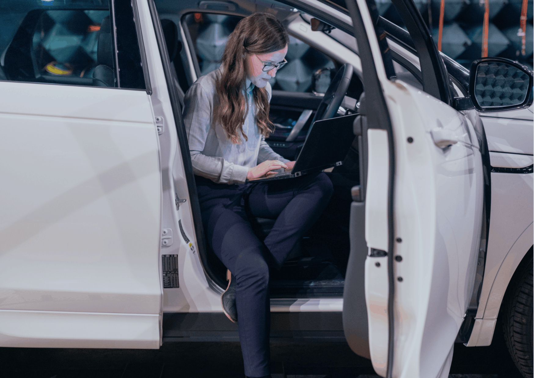 Fleet manager reviewing claims on a laptop beside a vehicle.